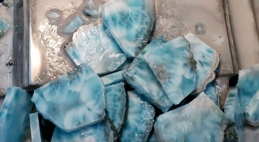 Cut Larimar slices. There is blue and white marbling with rare black spots, a natural occurence.