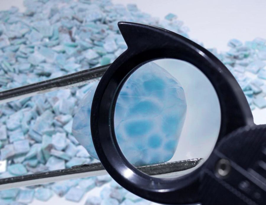 Small slices of Larimar on the table through a magnifying glass to inspect the quality of Larimar.
